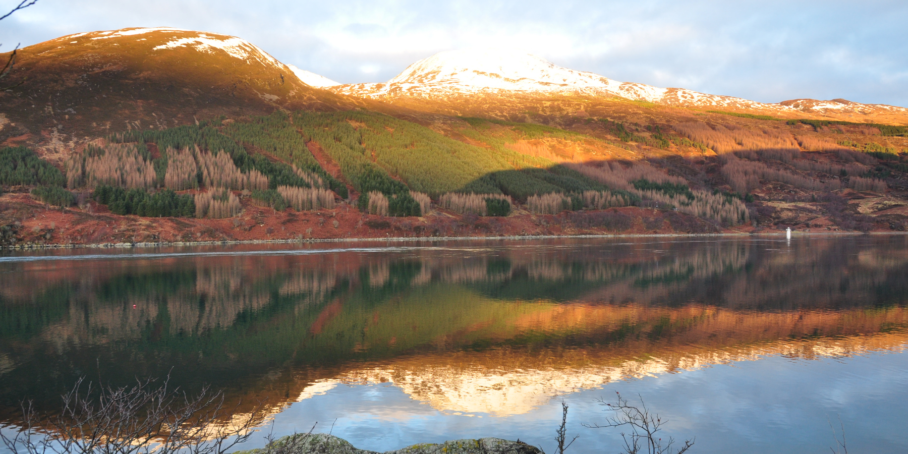 hills in autumn colours reflected in calm sea